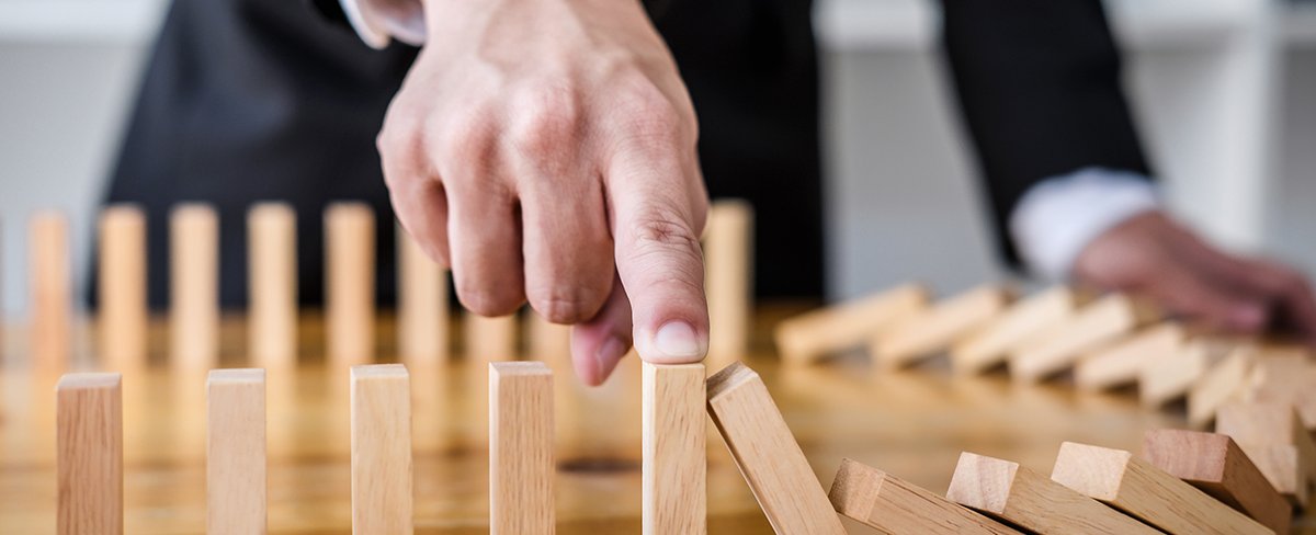 Holzspielstrategie. Ein Mann im Anzug hält einen Bauklotz mit dem Finger fest